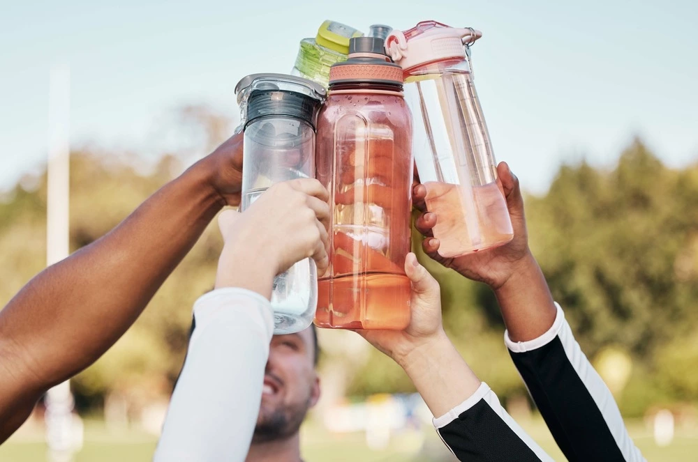 group of people holding water bottles up in a cheer