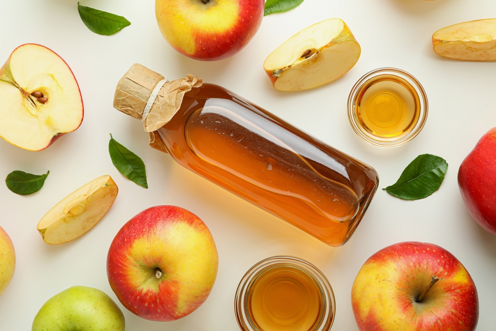 bottle of apple cider vinegar surrounded by apples