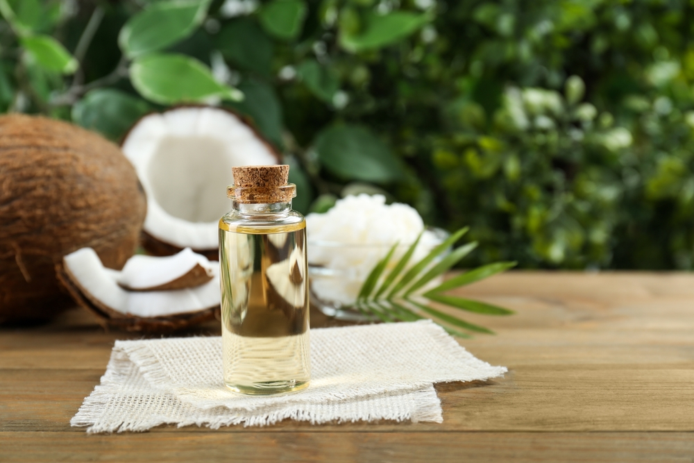 bottle of coconut oil in front of cut coconuts