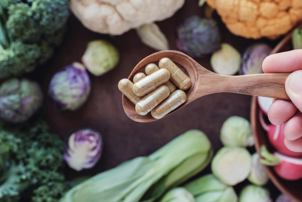 wooden spoon filled with fiber supplements over high-fiber vegetables