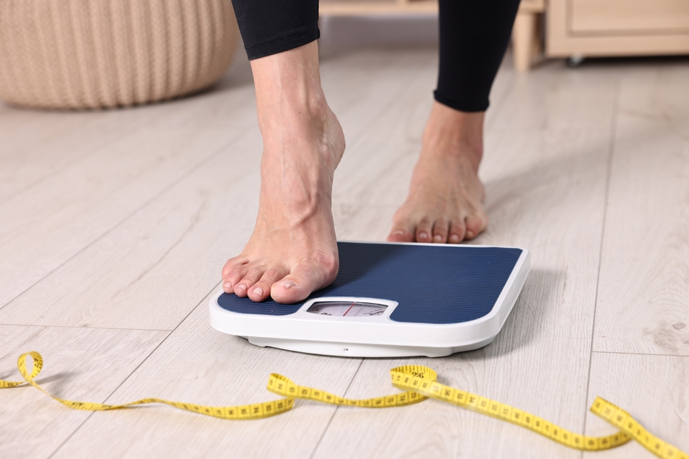 feet stepping on floor scale with tape measure on floor